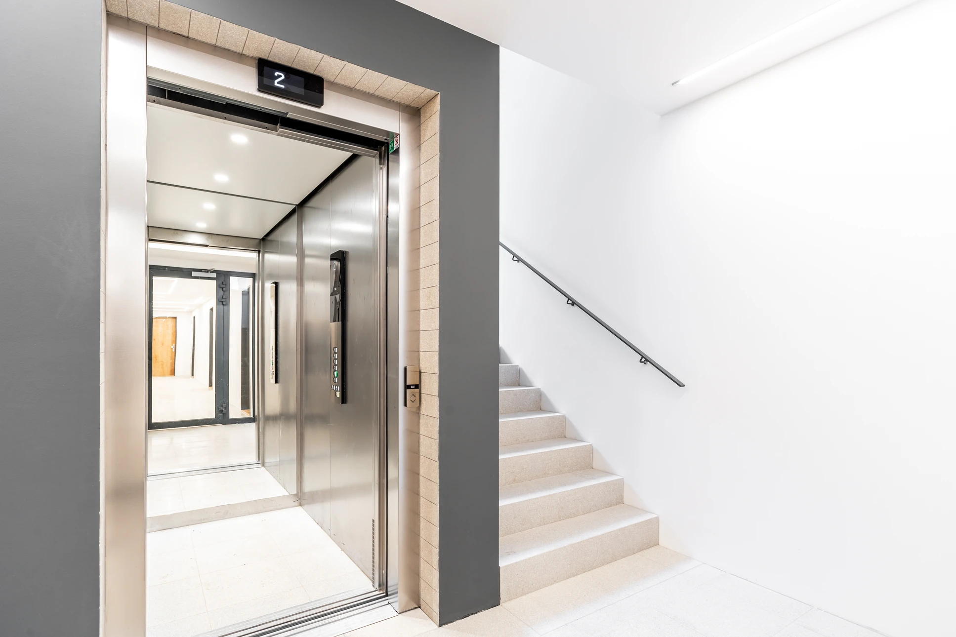 Hall d'entrée moderne avec ascenseur en acier inoxydable et escalier en bois
