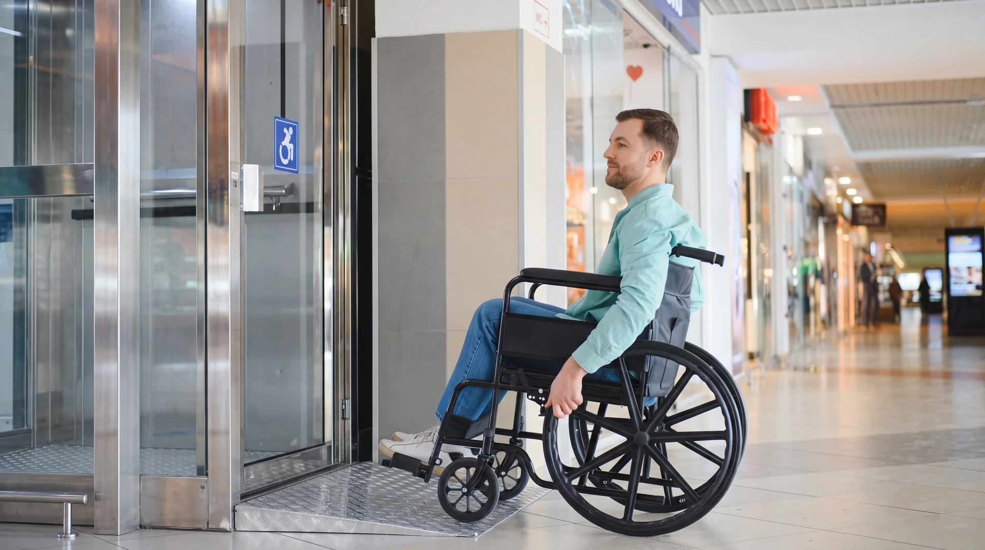 Photographie d'une plateforme élévatrice moderne installée à l'entrée ou à l'intérieur d'un immeuble, avec une personne en fauteuil roulant l'utilisant ou s'en approchant. La plateforme doit être clairement visible et fonctionnelle, intégrée dans un environnement architectural professionnel (bâtiment résidentiel, commercial ou public). L'image doit mettre l'accent sur l'accessibilité et l'intégration de l'équipement dans le bâti.